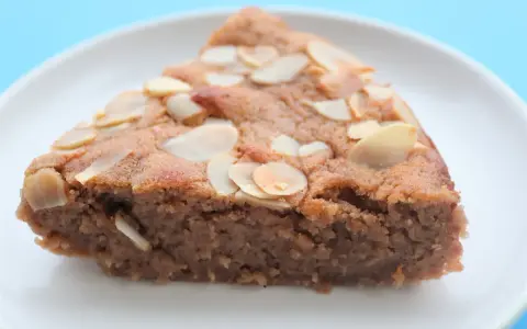 Tranche de gâteau à la crème de marron, garnie d'amandes effilées, sur une assiette blanche.