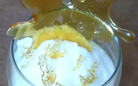 Un verre de crème aérienne surmonté d'une décoration en caramel craquant. Ces oeufs à la neige sont prêts à être dégustés.