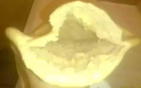 Une main tient un pain libanais ouvert, prêt à être garni. Sa texture moelleuse et sa poche invitent à la gourmandise.