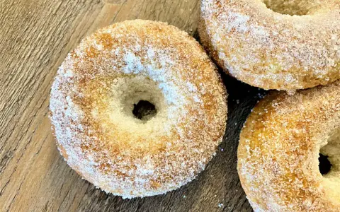 Trois donuts dorés, saupoudrés de sucre, prêts à être dégustés. Une recette donuts simple et gourmande.