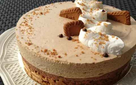Gâteau à la mousse légère, décoré de crème fouettée, de pépites de chocolat et de biscuits speculoos croustillants.