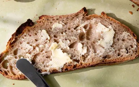 Tranche de pain de campagne, généreusement beurrée, prête à être dégustée. Une invitation à la simplicité et au bon goût.