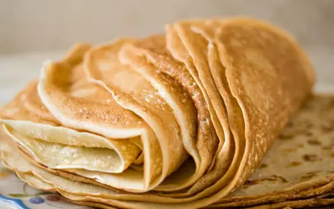 Pile de crêpes dorées, parfaites pour une recette crêpe sans beurre. Elles sont fines et légères, prêtes à être garnies.