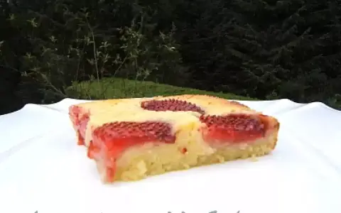 Un délicieux clafoutis aux fraises, tout juste sorti du four, sur une assiette blanche.