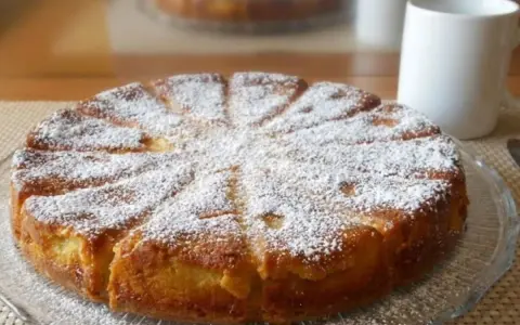 Gâteau mascarpone saupoudré de sucre glace, prêt à être dégusté avec une tasse de café.