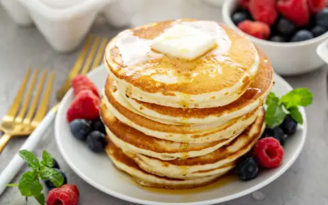 Pile de pancakes sans oeuf, dorés et moelleux, garnis de beurre fondant et de fruits rouges frais. Un délice pour le petit-déjeuner !