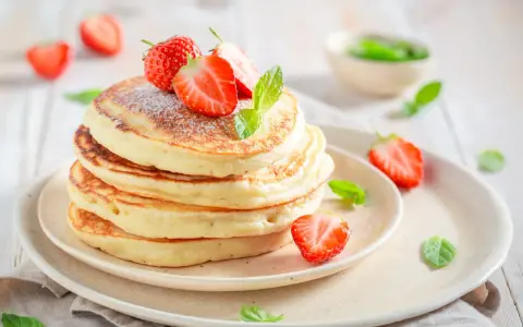 Pile de pancakes moelleux, décorés de fraises fraîches et de menthe, comme ceux de Cyril Lignac. Un délice !