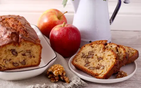 Un délicieux gâteau aux pommes et noix de grand-mère, avec des tranches présentées sur une assiette.