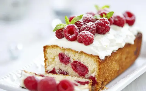 Un délicieux framboisier gateau, garni de framboises fraîches et de crème fouettée, prêt à être dégusté.