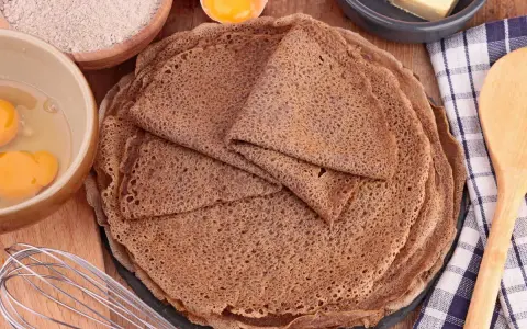 Pile de crêpes de sarrasin, avec des ingrédients pour la pâte à crêpe sarrasin : farine, œufs, beurre.