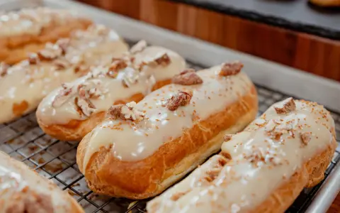 Éclairs dorés sur une grille, nappés d'un glacage sirop d'érable et parsemés de noix concassées. Un délice gourmand.
