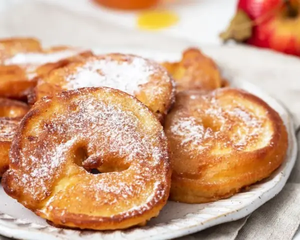 Délicieux beignets aux pommes saupoudrés de sucre glace, prêts à être dégustés.