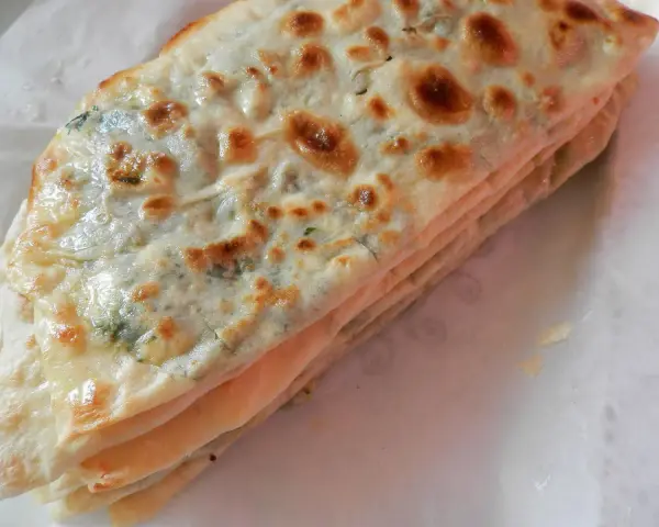 Gozleme épinard, une crêpe turque dorée et pliée, garnie d'épinards frais et savoureux.