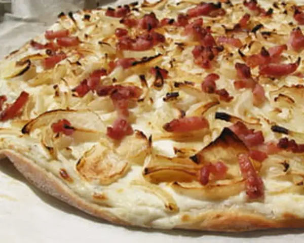 Flammekueche croustillante, garnie d'oignons et de lardons. Une recette simple et savoureuse pour un apéritif ou un repas léger.