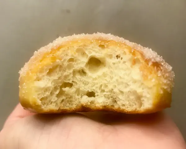 Gros plan d'un beignet sucré, sa mie aérée parfaite pour une recette beignet maison.