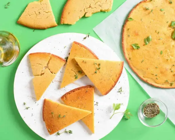 Une délicieuse socca coupée en parts, garnie d'herbes fraîches. Parfait pour une recette facile et savoureuse.