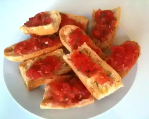 Des tranches de pain grillé garnies de tomates fraîches et d'herbes. Un délice simple et savoureux, parfait pour un apéritif.