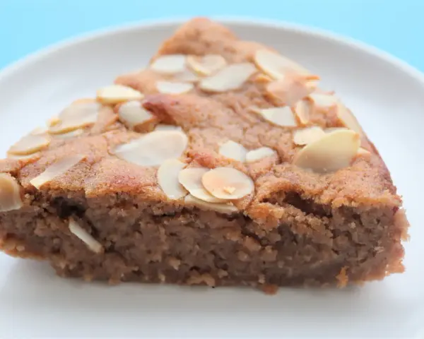 Tranche de gâteau à la crème de marron, garnie d'amandes effilées, sur une assiette blanche.