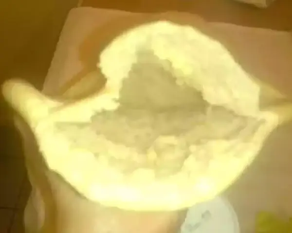 Une main tient un pain libanais ouvert, prêt à être garni. Sa texture moelleuse et sa poche invitent à la gourmandise.