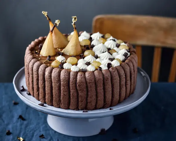 Charlotte poire chocolat, un gâteau élégant avec des poires pochées dorées, de la crème fouettée et des éclats de chocolat.