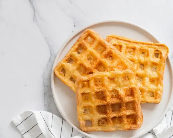 Trois gaufres au sarrasin dorées et croustillantes sur une assiette blanche, prêtes à être dégustées.