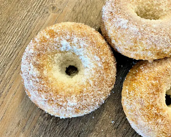 Trois donuts dorés, saupoudrés de sucre, prêts à être dégustés. Une recette donuts simple et gourmande.