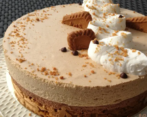 Gâteau à la mousse légère, décoré de crème fouettée, de pépites de chocolat et de biscuits speculoos croustillants.