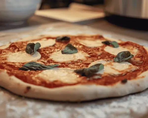 Une délicieuse pizza Margherita, avec sa pâte à pizza maison, prête à être dégustée. Un vrai délice pour les amateurs de pain et de bonnes choses.