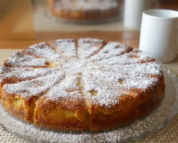 Gâteau mascarpone saupoudré de sucre glace, prêt à être dégusté avec une tasse de café.