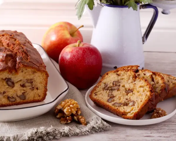 Un délicieux gâteau aux pommes et noix de grand-mère, avec des tranches présentées sur une assiette.