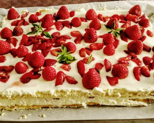 Un délicieux entremet fraise, garni de fruits rouges frais et de feuilles de menthe, sur une base crémeuse.