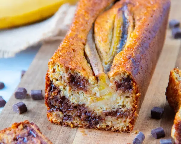 Un délicieux banana bread aux pépites de chocolat, garni de bananes sur le dessus, prêt à être dégusté.