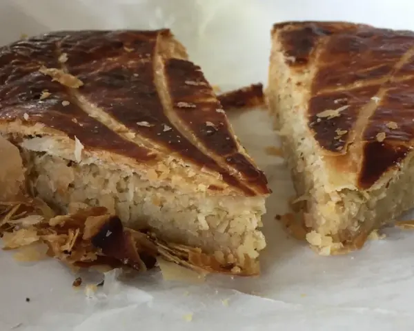Deux parts de galette des rois coco, avec leur feuilletage doré et leur garniture généreuse, prêtes à être dégustées.