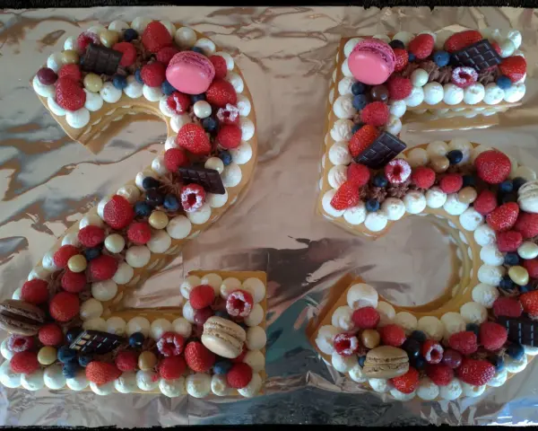 Gâteau chiffre 25 décoré de chantilly mascarpone, framboises, fraises, myrtilles, macarons et chocolat.