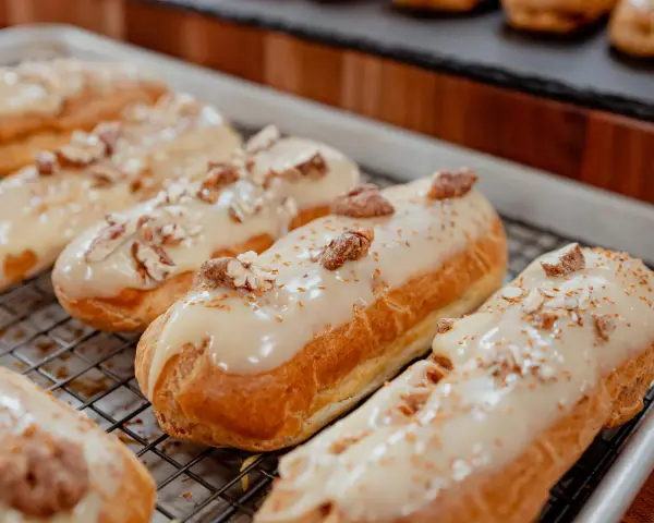 Éclairs dorés sur une grille, nappés d'un glacage sirop d'érable et parsemés de noix concassées. Un délice gourmand.