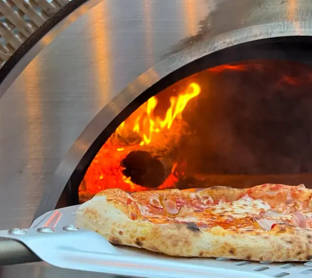 Une délicieuse pizza maison sortant d'un four à bois ardent.