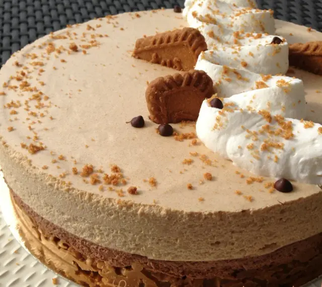 Gâteau à la mousse légère, décoré de crème fouettée, de pépites de chocolat et de biscuits speculoos croustillants.