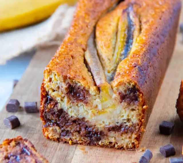 Un délicieux banana bread aux pépites de chocolat, garni de bananes sur le dessus, prêt à être dégusté.