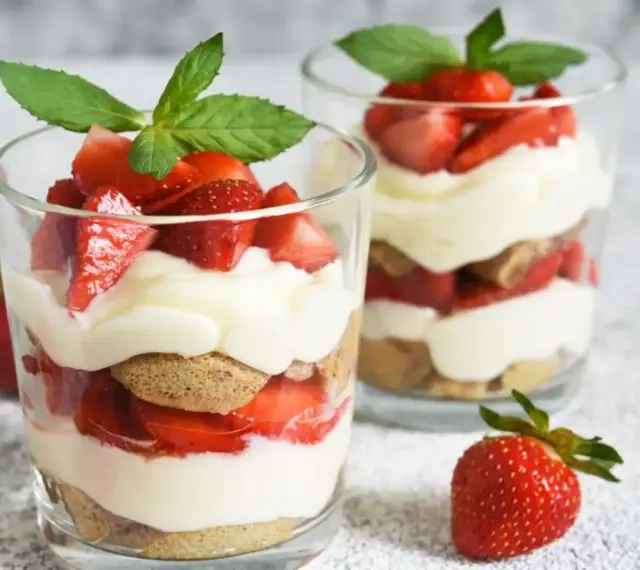 Deux verrines de tiramisu fraise, garnies de fruits rouges frais et de feuilles de menthe.