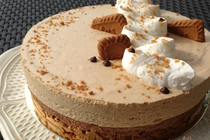 Gâteau à la mousse légère, décoré de crème fouettée, de pépites de chocolat et de biscuits speculoos croustillants.