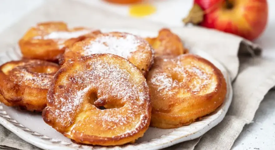 Délicieux beignets aux pommes saupoudrés de sucre glace, prêts à être dégustés.