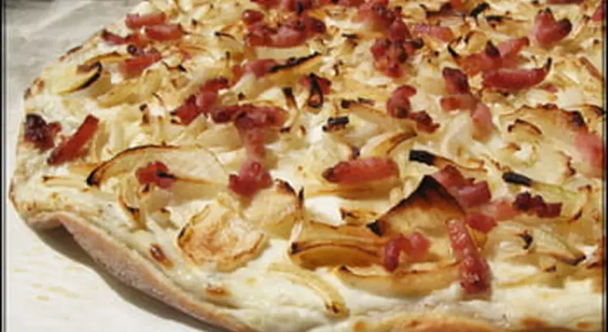 Flammekueche croustillante, garnie d'oignons et de lardons. Une recette simple et savoureuse pour un apéritif ou un repas léger.