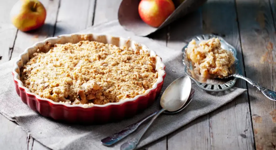 Un délicieux crumble pomme tout juste sorti du four, prêt à être dégusté. Des pommes fondantes sous une couche croustillante.