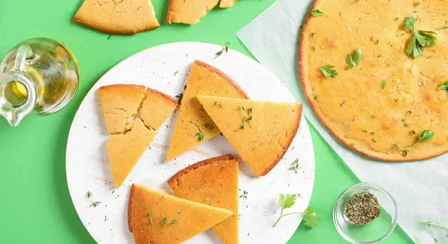 Une délicieuse socca coupée en parts, garnie d'herbes fraîches. Parfait pour une recette facile et savoureuse.