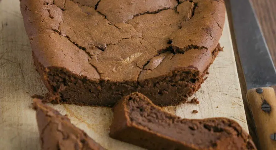 Un délicieux gâteau au chocolat en forme de cœur, un gâteau sans oeuf, craquelé sur le dessus, avec une part coupée.