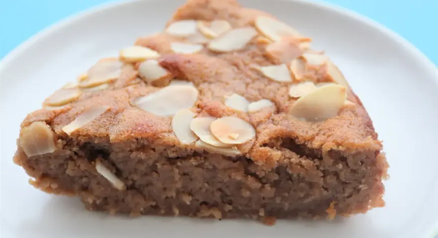 Tranche de gâteau à la crème de marron, garnie d'amandes effilées, sur une assiette blanche.