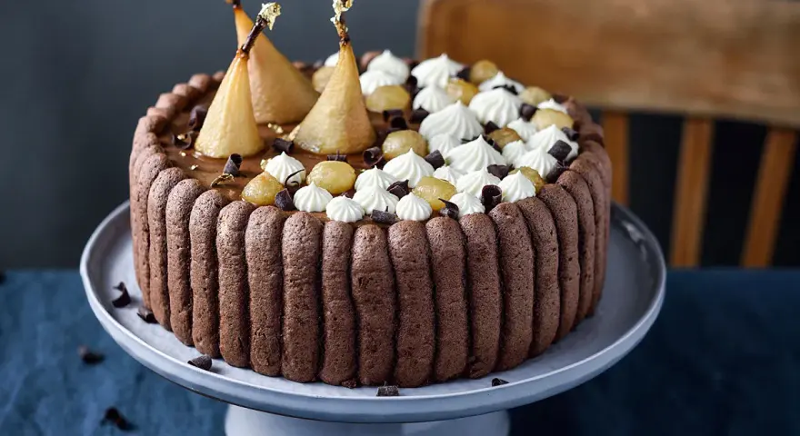 Charlotte poire chocolat, un gâteau élégant avec des poires pochées dorées, de la crème fouettée et des éclats de chocolat.