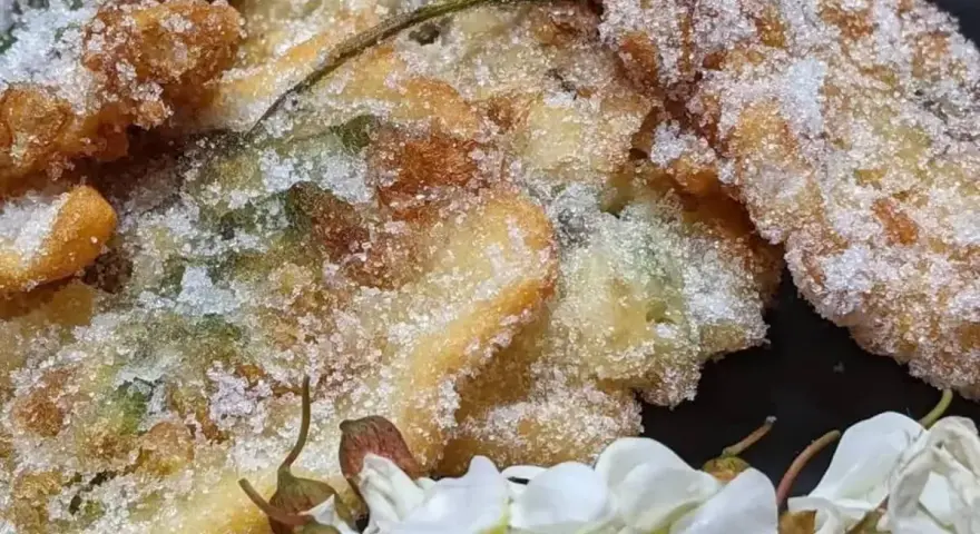 Délicieux beignets d'acacia, croustillants et saupoudrés de sucre, accompagnés de fleurs blanches.