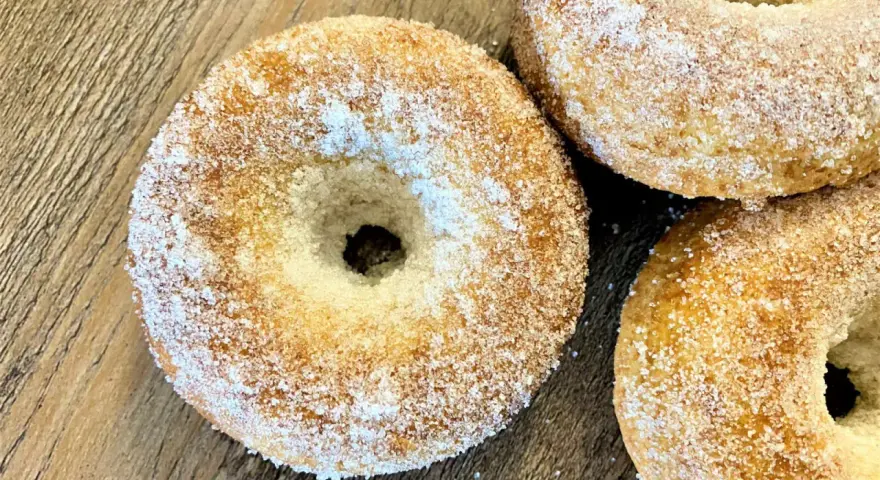 Trois donuts dorés, saupoudrés de sucre, prêts à être dégustés. Une recette donuts simple et gourmande.