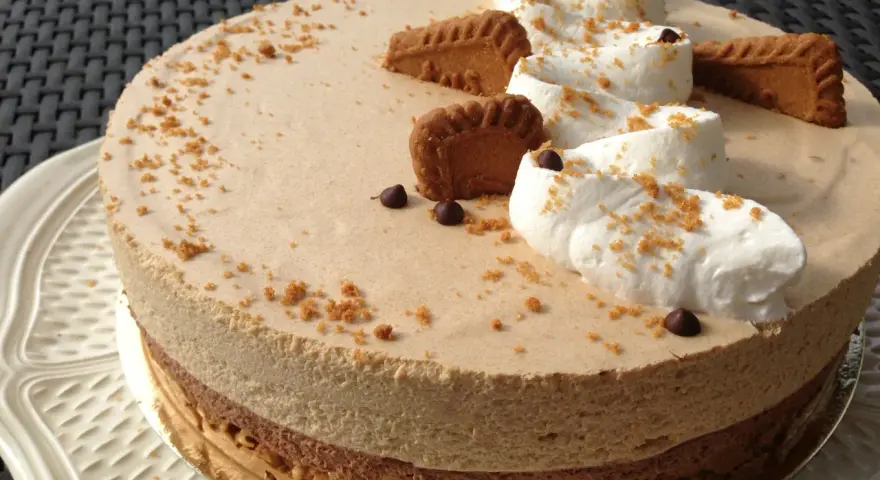 Gâteau à la mousse légère, décoré de crème fouettée, de pépites de chocolat et de biscuits speculoos croustillants.
